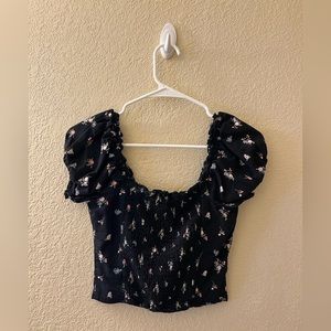 Black shirt with pink and blue flower detailing. Black buttons down the center.